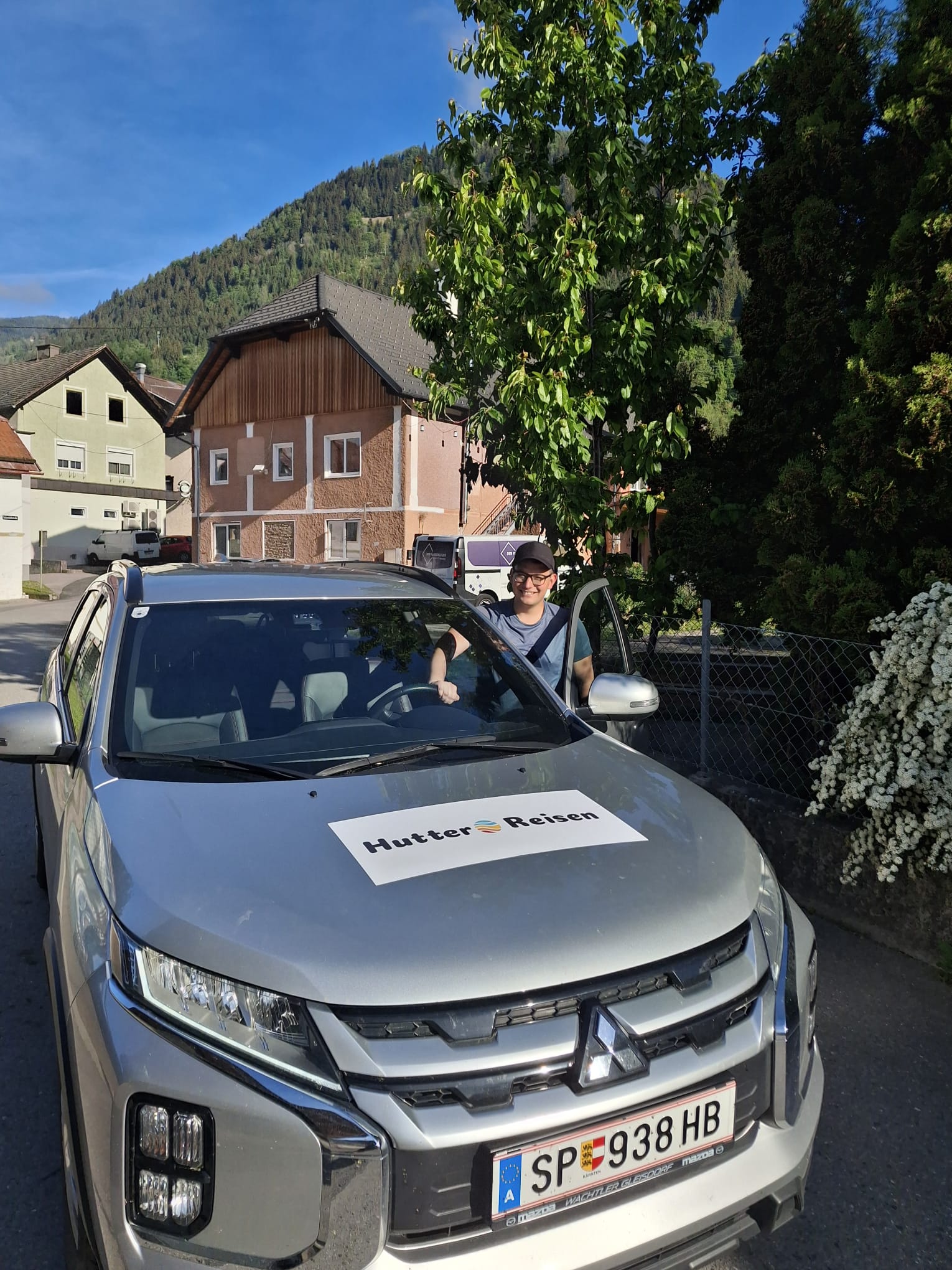 Florian steigt in eines der Hutter-Reisen-Autos, Firmenschild handgemacht am Armaturenbrett
